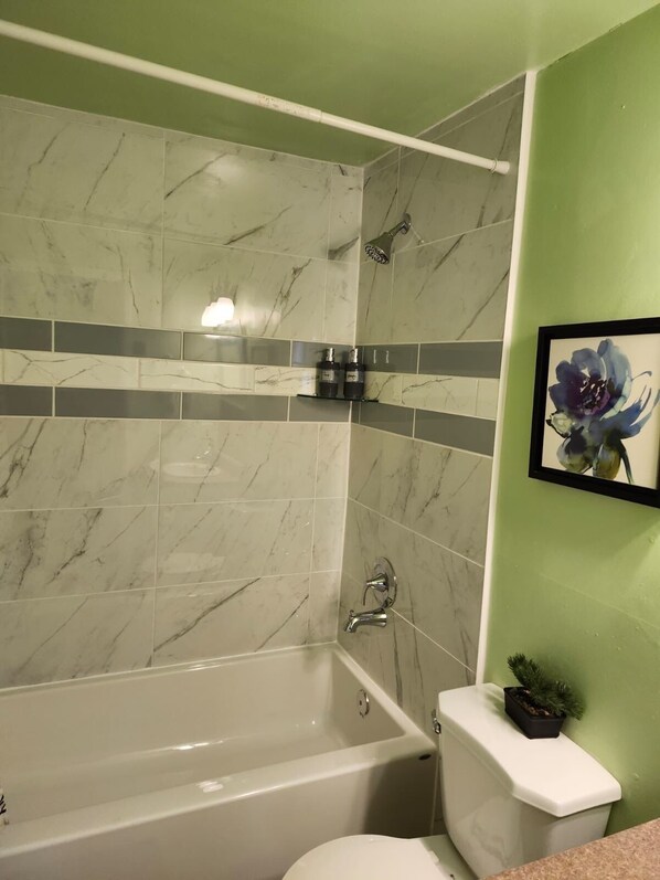A bathroom with a bathtub, a toilet, and a shower.