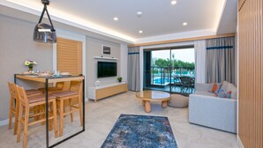 A modern living room with a dining area, a TV, a pool view, and a cozy seating area. - A Suite Side (Manavgat)