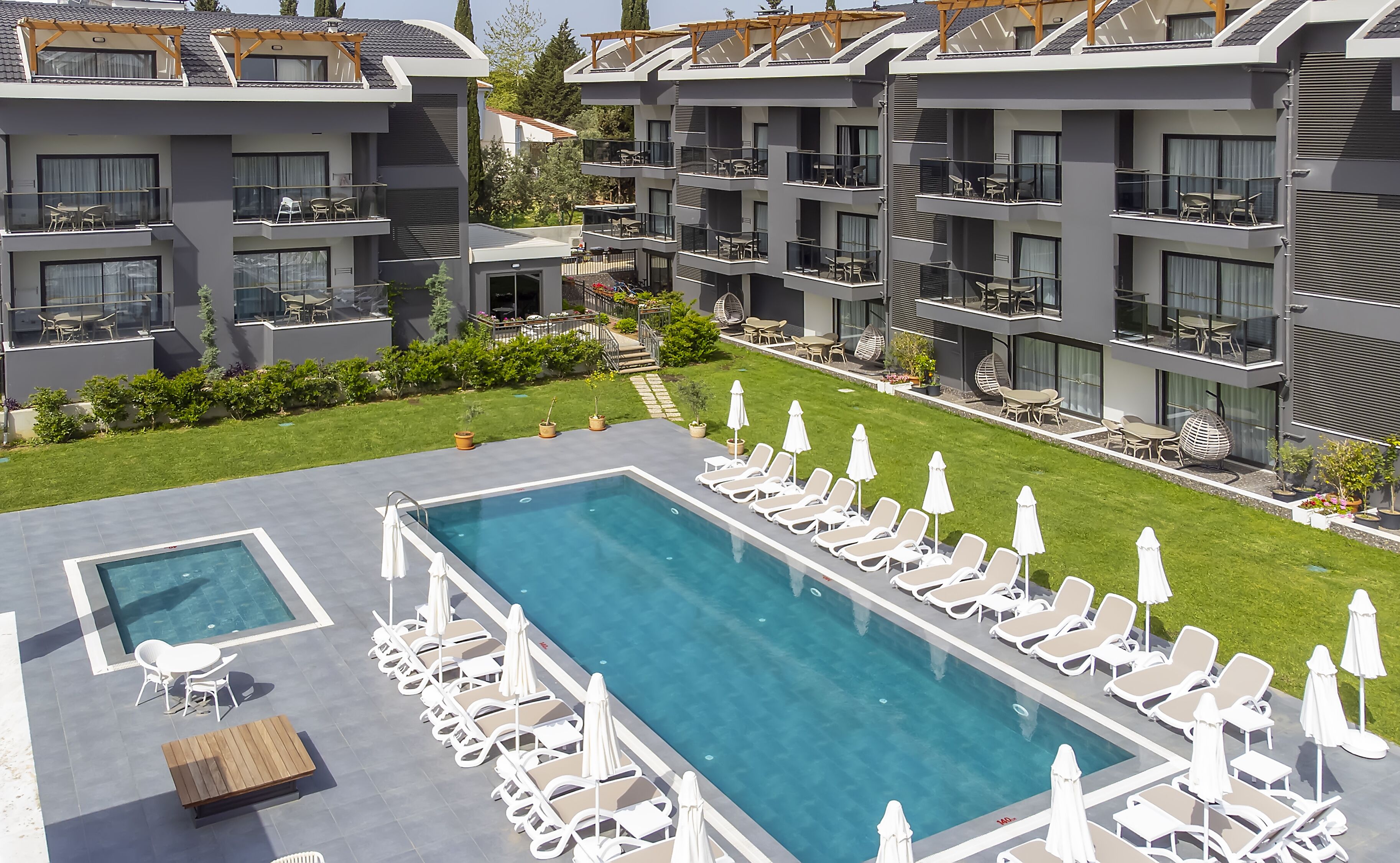 Un hôtel moderne doté d’une grande piscine extérieure, de nombreux balcons aménagés avec du mobilier de jardin et d’une pelouse bien entretenue.