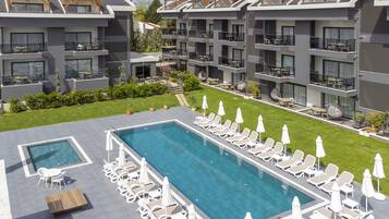 Un hôtel moderne doté d’une grande piscine extérieure, de nombreux balcons aménagés avec du mobilier de jardin et d’une pelouse bien entretenue.