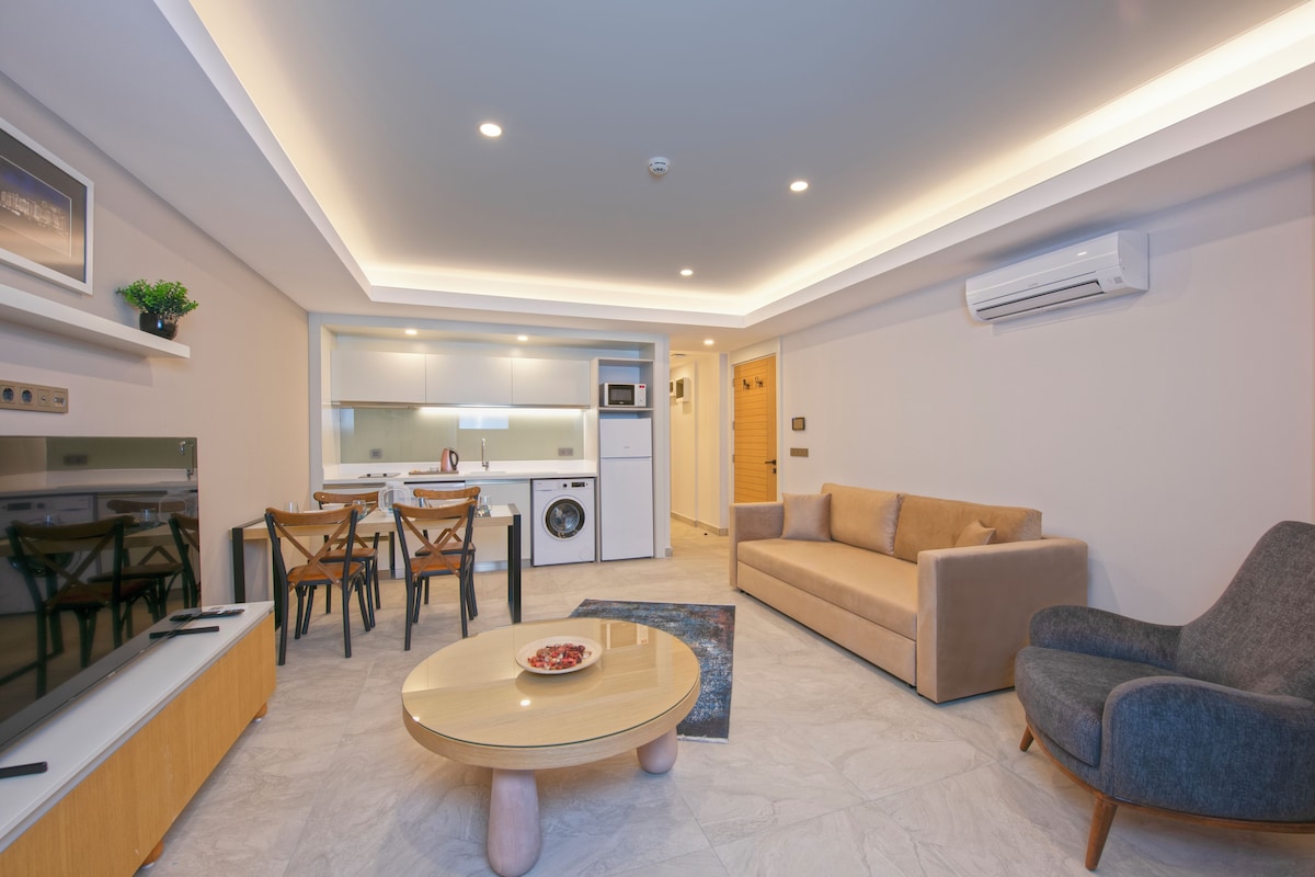 A modern living room with a sofa, a round coffee table, and a dining area with chairs and a table.