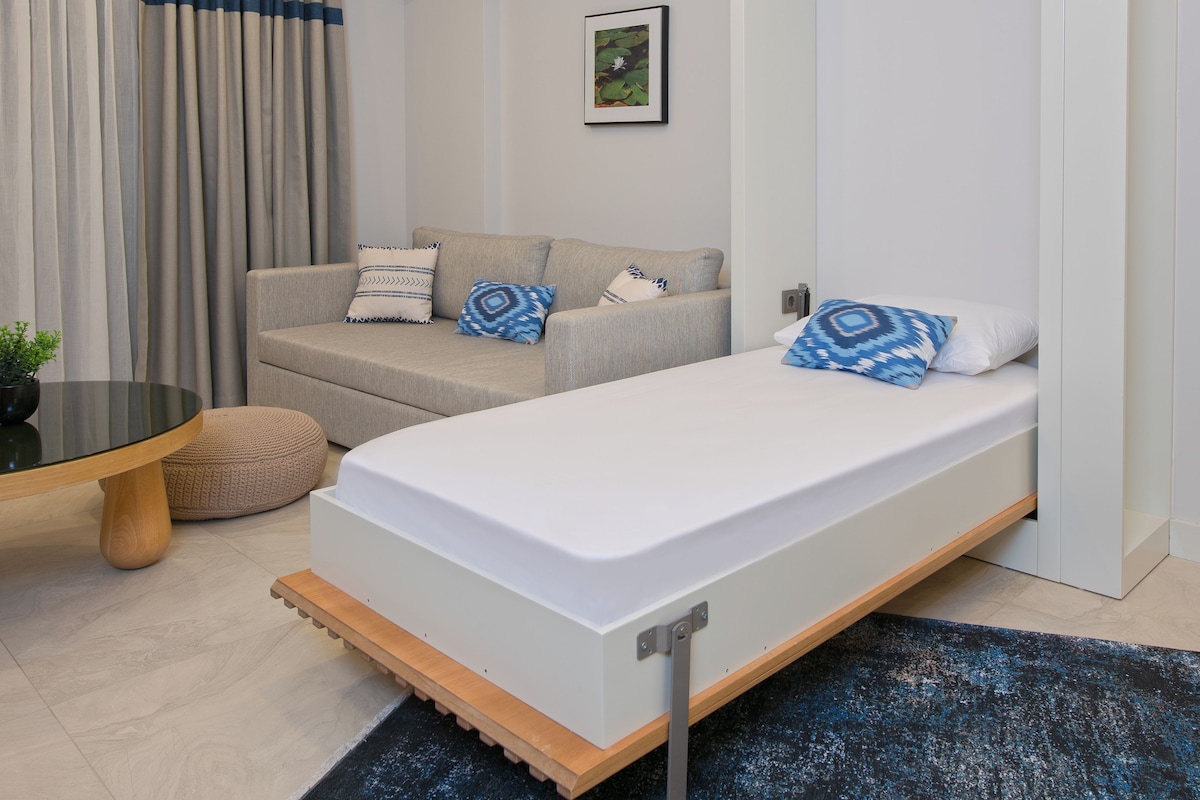 A compact bedroom with a bed, a sofa, and a small table.