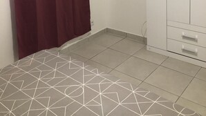 A room with a geometric patterned rug, a white wardrobe with two doors, and a red curtain. - Magnificent apartment 2 km from the beach (Le Gosier)