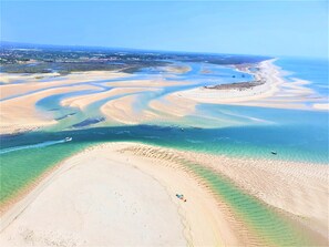 Une vue aérienne d’une zone côtière, avec des eaux cristallines, des plages de sable et un bateau sur l’eau.
