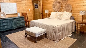 Ein gemütliches Zimmer mit Holzboden, einem Bett, einer Kommode und einem Sessel.