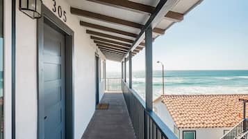 A balcony with a view of the ocean, a door labeled '305', and a tiled roof in the background.