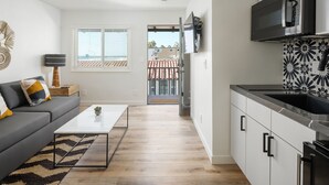 Una cocina moderna con armarios blancos, encimera negra y microondas integrado.