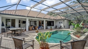 A covered outdoor area with a swimming pool, patio furniture, and a tiled roof.