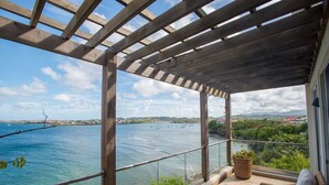Ein Balkon mit einer Pergola, einer hölzernen Bank und einem Blumentopf.