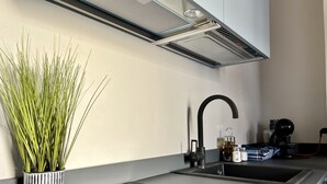 A modern kitchen with a sleek black faucet, a stainless steel range hood, and a black induction cooktop. - Suite Amalfitania, Ortigia, Syracuse. (Siracusa)