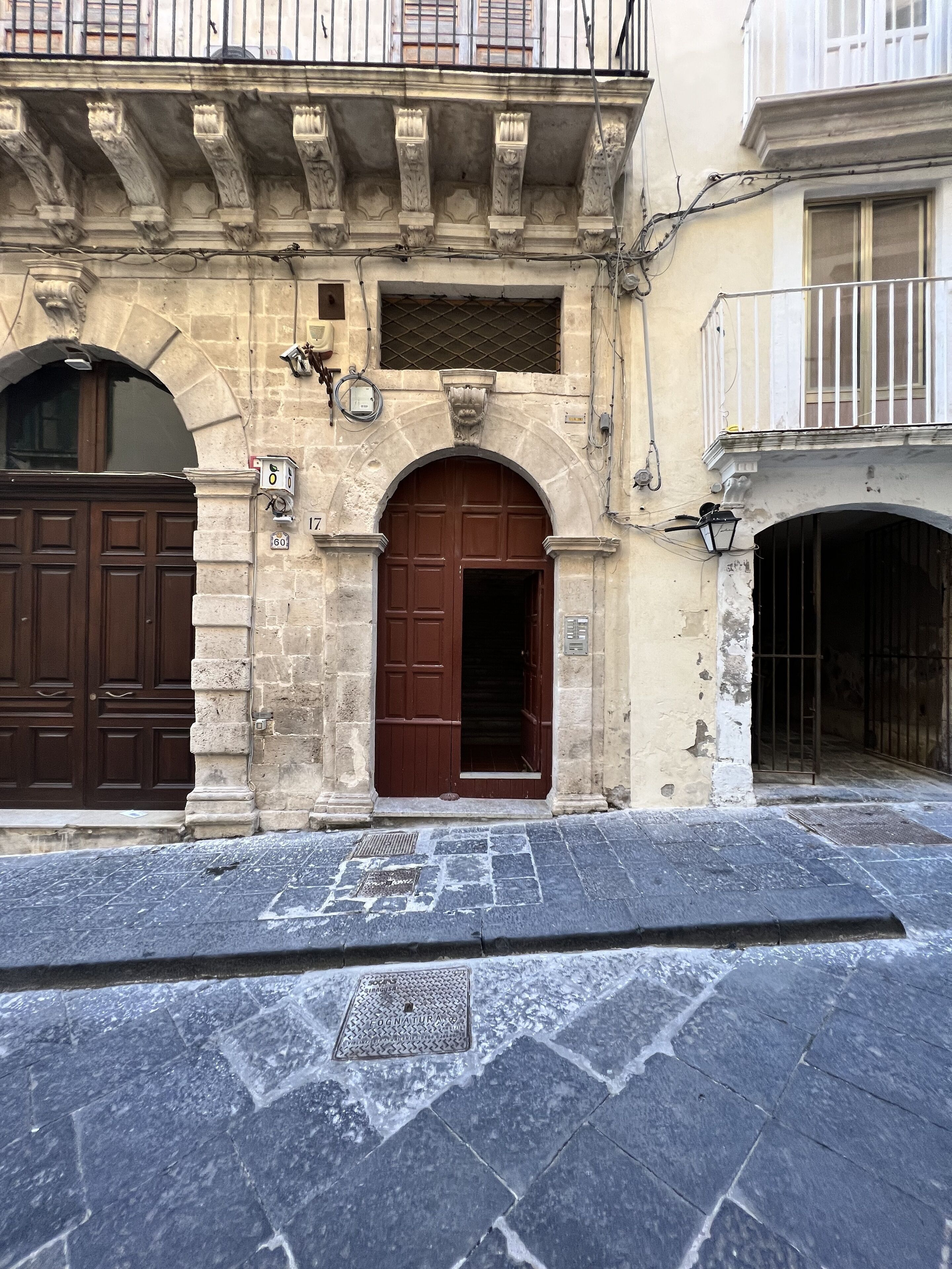 Un bâtiment historique doté d’un portail central en arc de cercle, d’une grande porte en bois et d’une façade en pierre.