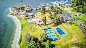 Ilmakuva rannikkoalueella sijaitsevasta kiinteistöstä, jossa on venesatama, tenniskentät ja ranta.