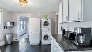 Een moderne keuken met een wasmachine, een magnetron, een koffiezetapparaat en een broodrooster.
