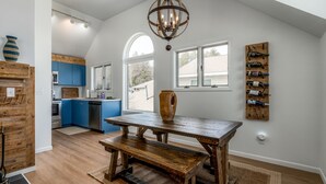 A spacious kitchen with a wooden table and bench, blue cabinets, and a wine rack on the wall. - Fish Creek Beach House, Grandview Condo: Entire Top Floor - 4 Bed, 2 Bath (Fish Creek)