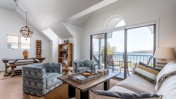 A spacious living area with a large window, a wooden coffee table, and a sofa. - Fish Creek Beach House, Grandview Condo: Entire Top Floor - 4 Bed, 2 Bath (Fish Creek)