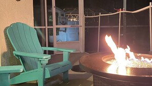 Eine Terrasse mit Feuerstelle und zwei grünen Adirondack-Stühlen.