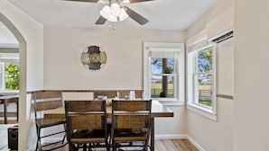 A dining area with a ceiling fan, wooden chairs, a table, and a window with a view of the outdoors.