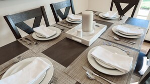 A dining table set with white plates, napkins, and cutlery, featuring a central candle holder. - Updated home in safe, quiet neighborhood with lots of amenities! (San Diego)