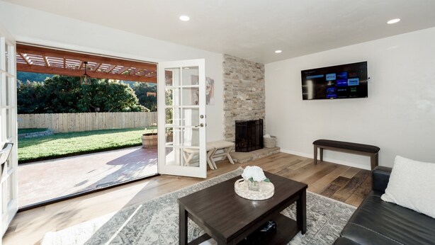 A modern living room with a fireplace, a TV mounted on the wall, and a large sliding glass door leading to a backyard. - Updated home in safe, quiet neighborhood with lots of amenities! (San Diego)