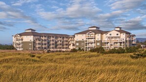A multi-story hotel with a flat roof and balconies, surrounded by a field of tall grass. - Long Beach WA  Oceanfront 4th of July week (Long Beach)