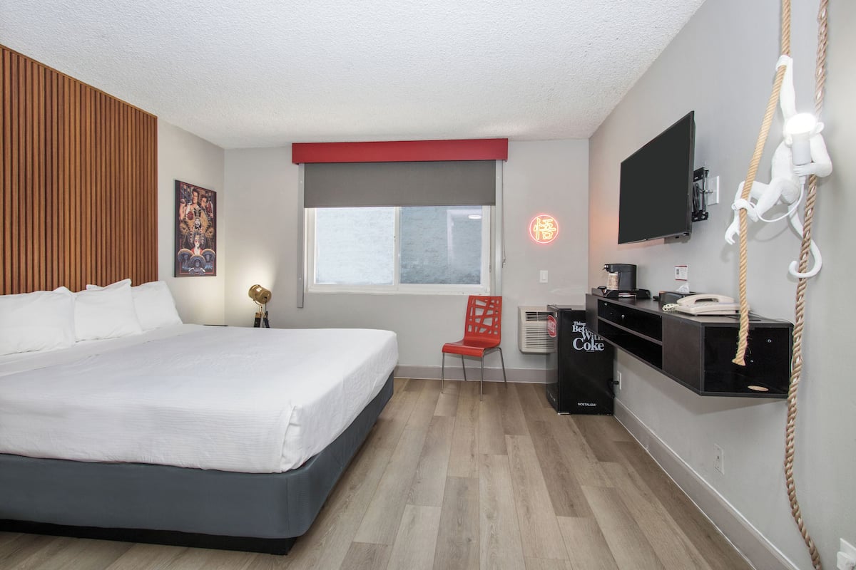 Una habitación de hotel con cama, escritorio, silla, televisión y ventana.