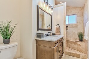 A bathroom with a marble sink, a large mirror, and a potted plant.