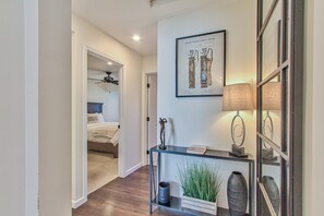 A hallway with a ceiling fan, a framed patent office illustration, a console table with a lamp, and a vase.