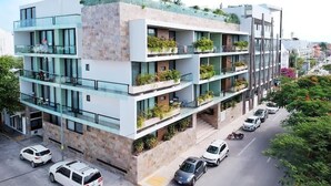Um edifício com várias andares, varandas, área de estacionamento e vista para a rua.