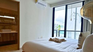Quarto com uma cama grande, um guarda-roupa de madeira, uma janela com vista e um aparelho de ar condicionado.
