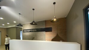 Ein modern gestalteter Empfangsbereich mit einer Rezeption, einem Schild mit der Aufschrift "RECEPTION" und drei Pendelleuchten.