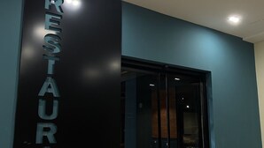 Ein moderner Restauranteingang mit Glastür und einem Schild mit der Aufschrift 'RESTAURANT' an der Wand.