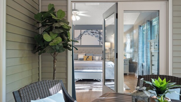 A room with a bed, a chair, a table, and a potted plant.