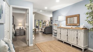 A spacious living room with a large white cabinet, a grey sofa, and a wooden coffee table.