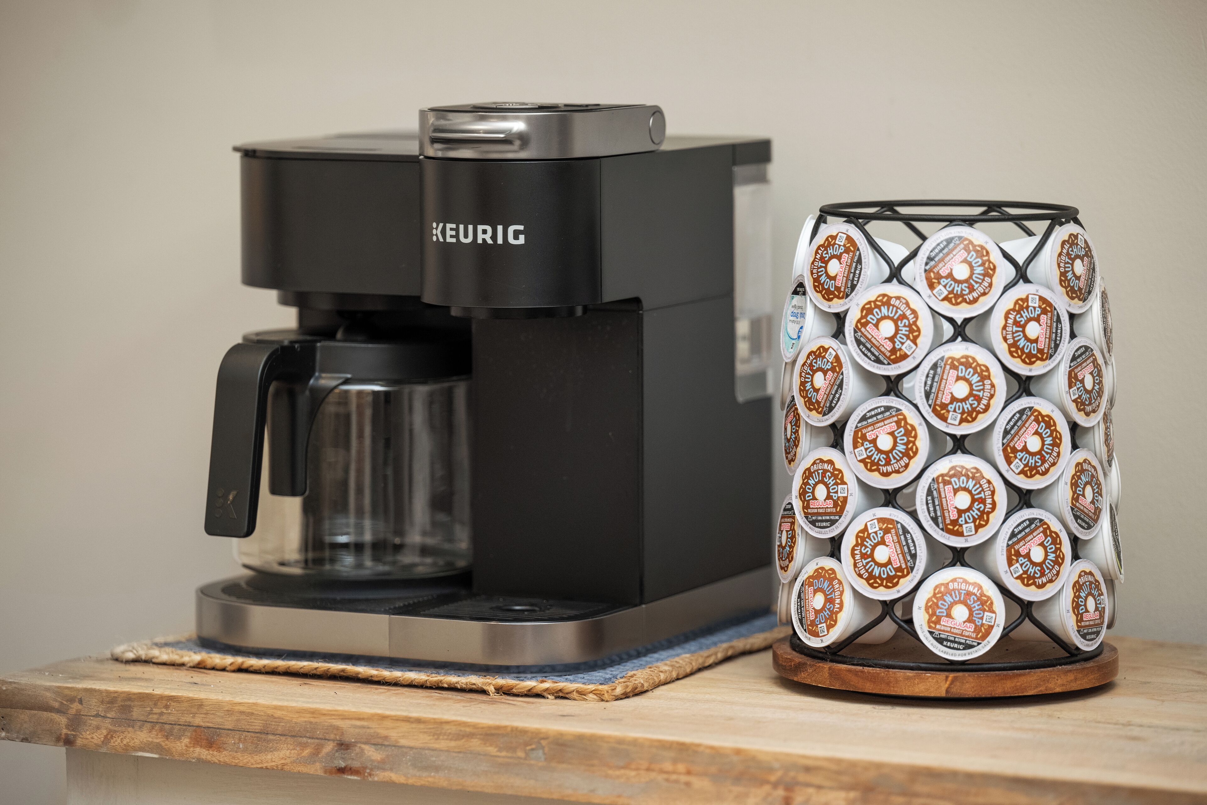A Keurig coffee maker and a stack of coffee pods on a wooden surface.