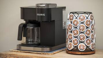 A Keurig coffee maker and a stack of coffee pods on a wooden surface.