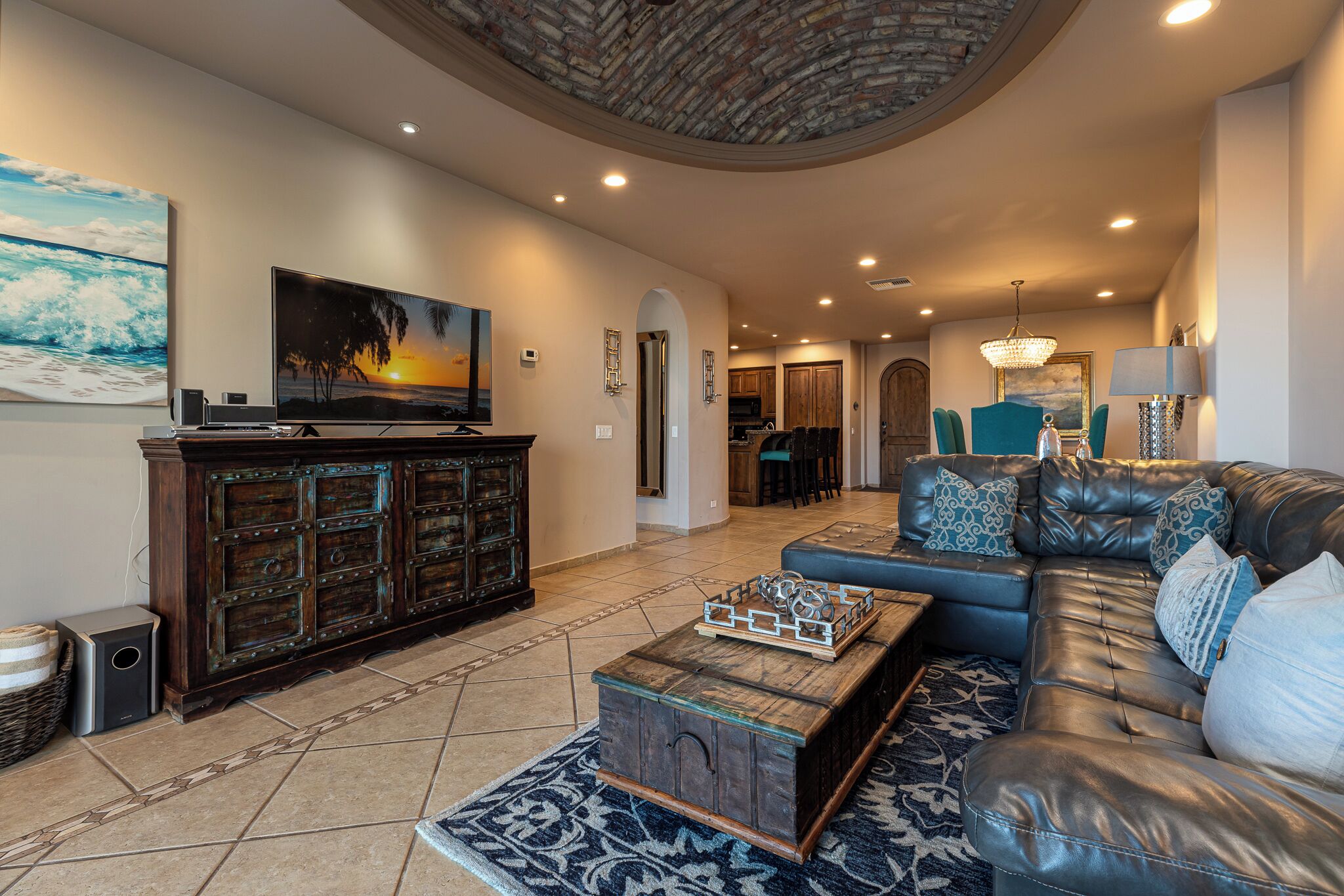 A spacious living room with a large sectional sofa, a wooden entertainment center, and a large flat-screen TV.