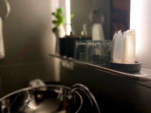 A bathroom counter with a hair care product display and a pair of glasses. - The Enlightened House (Amsterdam)