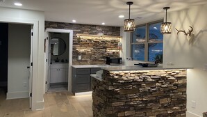 Una cocina moderna con una isla de piedra, iluminación empotrada y vistas al exterior.