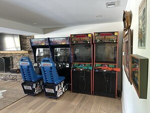 Une salle avec des jeux d’arcade, notamment « California Speed » et « Big Buck Hunter II », et une cheminée.