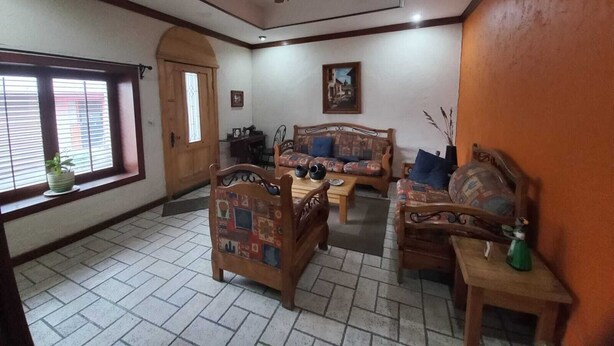 Un salon avec un ventilateur de plafond, une porte en bois, un canapé et une table basse.