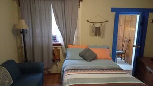 Une chambre à coucher avec un lit, un canapé bleu, une lampe et une porte qui donne sur une autre pièce.