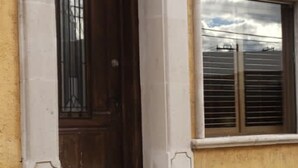 Un bâtiment à la façade jaune, doté d’une grande entrée en arc de cercle et d’une fenêtre avec des volets.
