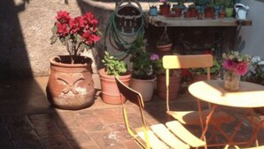 Une terrasse avec des pots en terre cuite, une table pliante et des chaises.