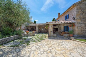 A stone courtyard with a covered seating area, stone walls, and potted plants. - Villa with air conditioning and pool (Sveti Lovreč)