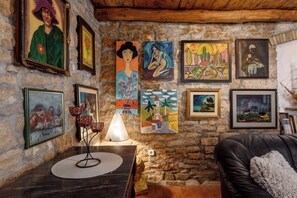 A cozy room with a stone wall, wooden ceiling, and various framed artworks. - Villa with air conditioning and pool (Sveti Lovreč)