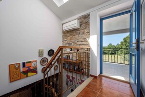 A staircase with a stone wall, a wooden railing, and a view of the outdoors through a blue door. - Villa with air conditioning and pool (Sveti Lovreč)