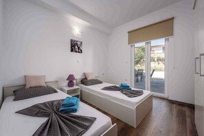 A modern hotel room with two beds, a large sliding glass door to the balcony, and a minimalist design. - Holiday apartment with shared pool, air conditioning (Nova Vas/Poreč)
