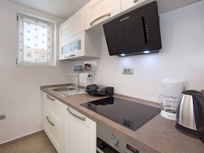 A compact kitchen with a built-in microwave, a coffee maker, and a kettle.