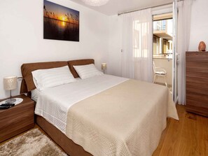 A bedroom with a bed, bedside tables, a lamp, a painting, and a view through a window. - Holiday apartment with balcony, air conditioning (Poreč)