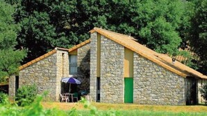 Un bâtiment en pierre avec un toit en pente, un petit porche avec une table et des chaises, et une porte verte.